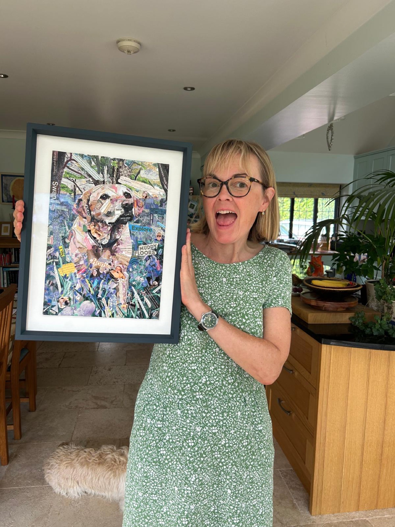 Woman in a green dress holding a framed collage dog portrait