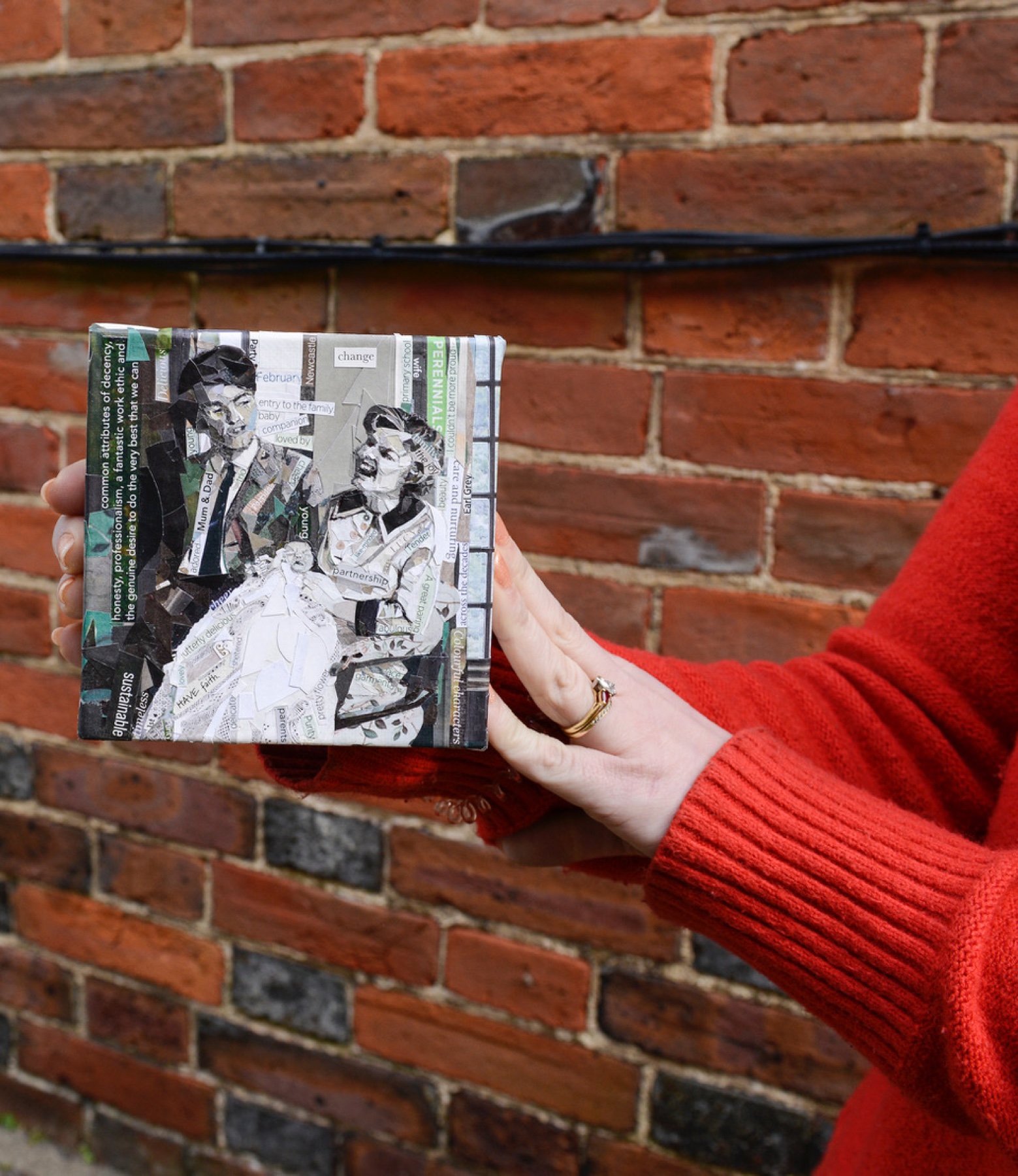 Hands in a red jumper holding a framed collage family portrait